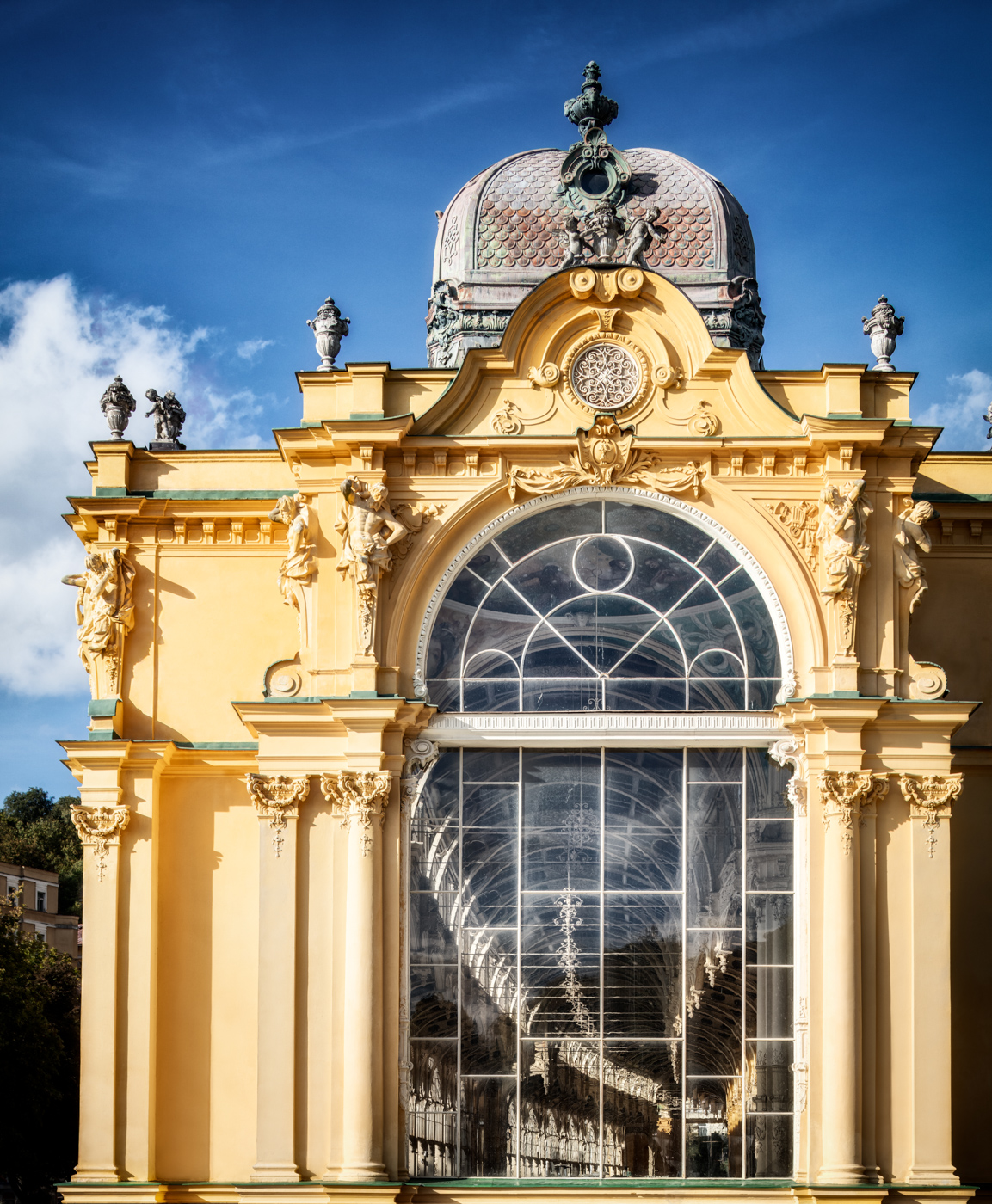 Yellow end pavilion of the Main Colonnade in Marienbad with a large glass window, sculptures and a dome