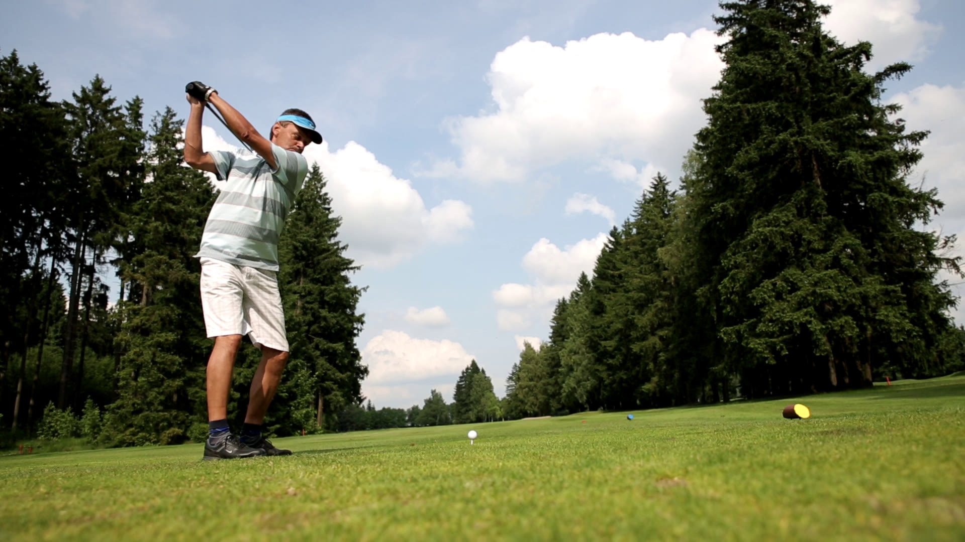 Golfový švih na hřišti mezi lesy