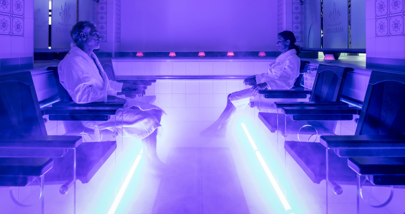 Spa guests sitting at the edge of the warm carbonated pool with their legs in the water