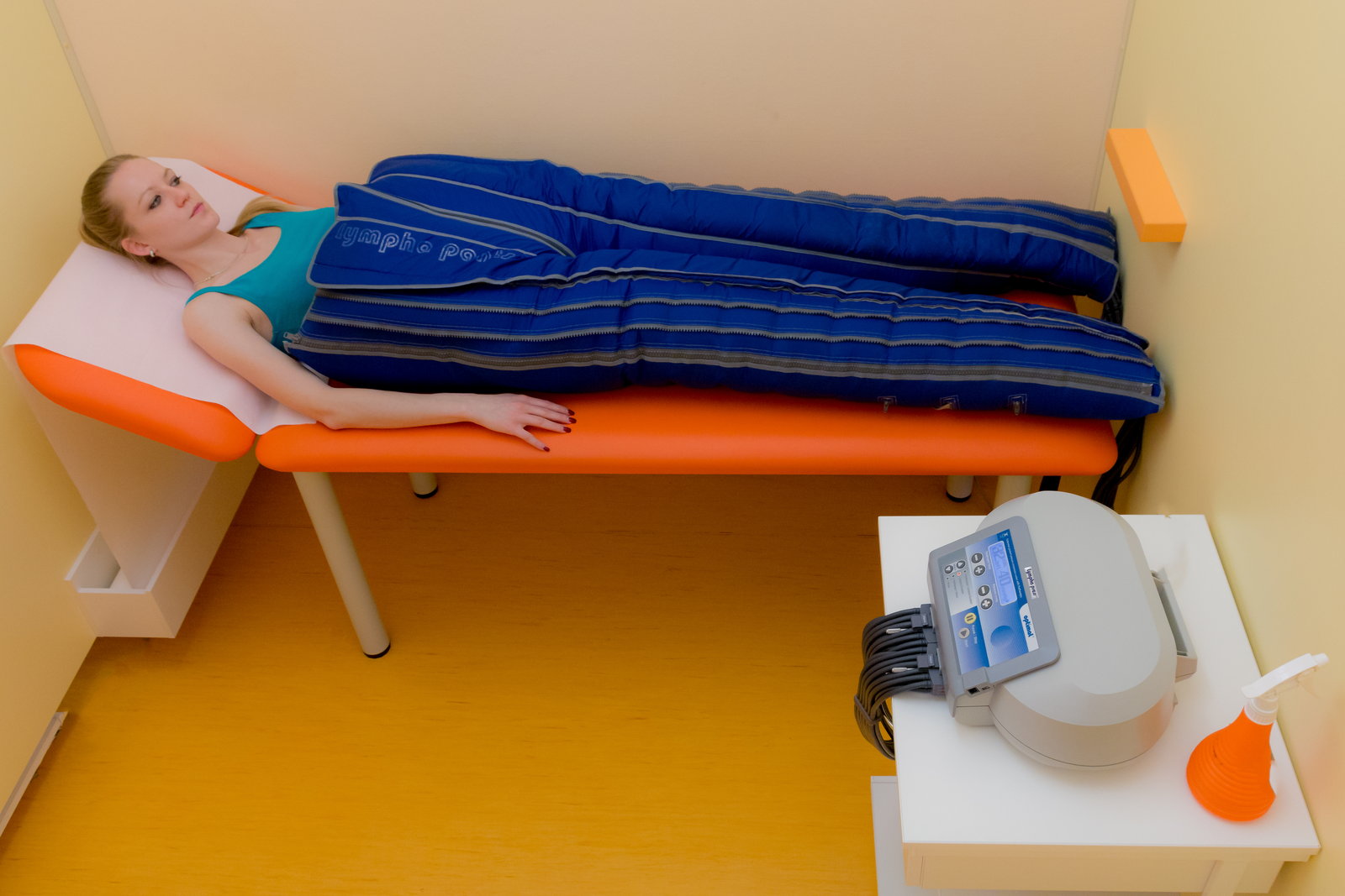 Klientka s nohama v modrých pneumatických rukávech při přístrojové lymfodrenáži