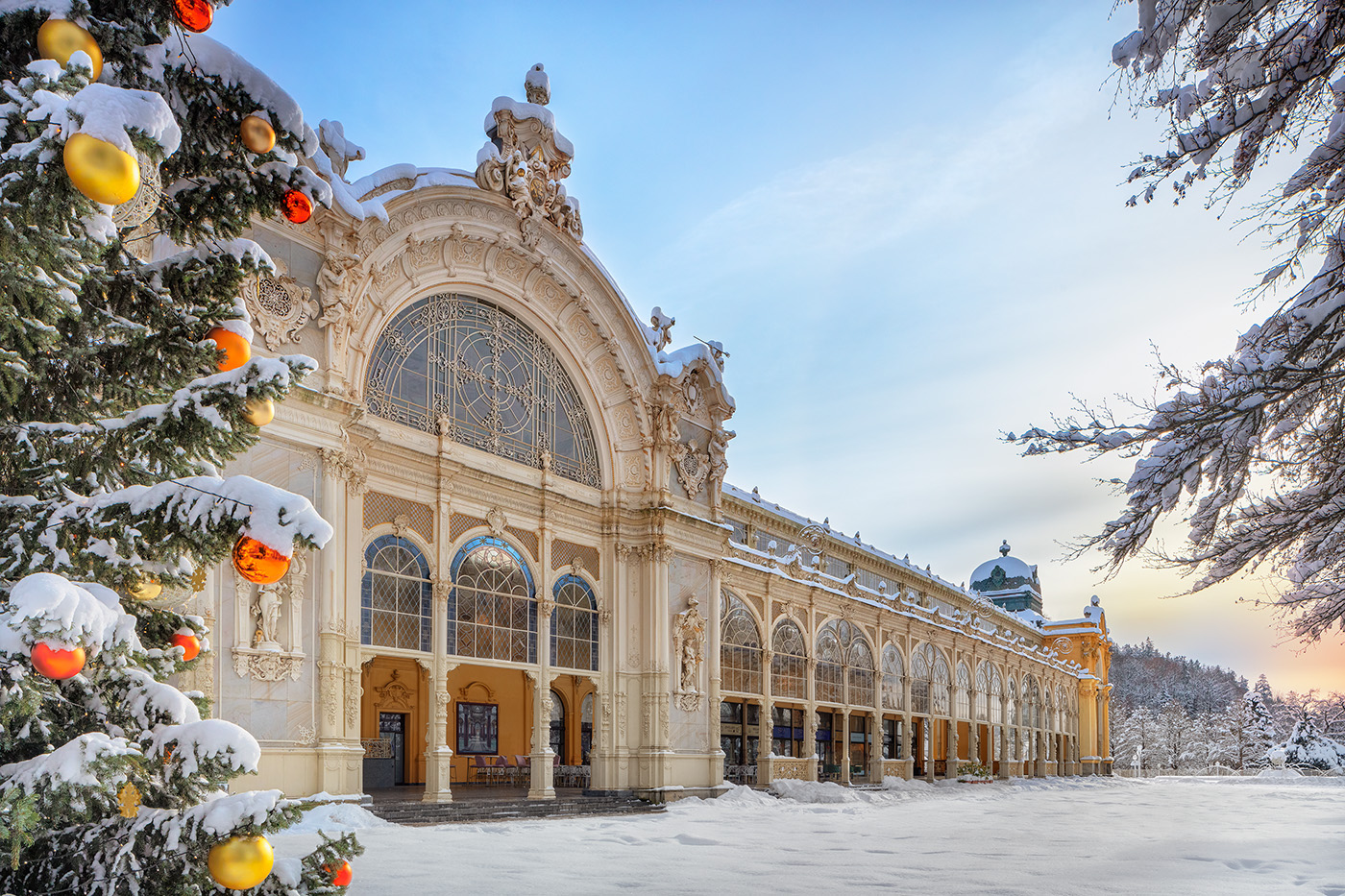 Snow-covered main colonnade with a Christmas tree and baubles in the foreground